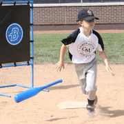 Young athlete practicing with Blitzball StrikeZone Target and bat on a sandy baseball field.