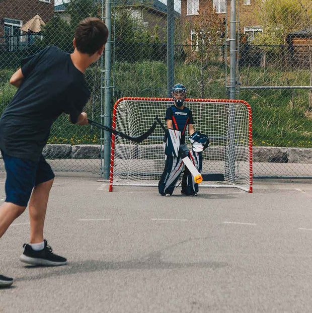 Road Warrior Street Hockey Balls - 15 Pack (Extreme Colours) in action at an outdoor rink with players and a net