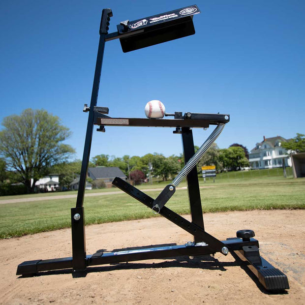 Louisville Slugger Black Flame pitching machine on baseball field with a baseball ready for practice