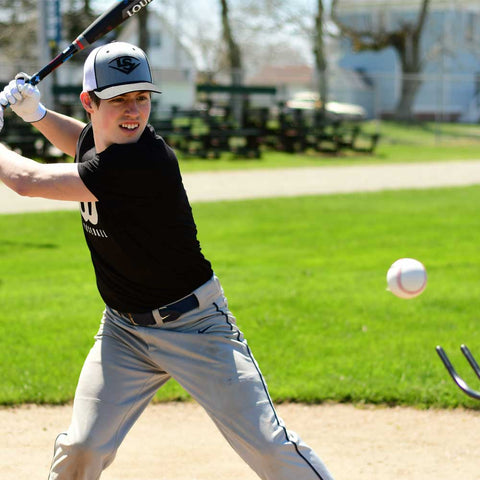 Young athlete using Louisville Slugger soft-toss system for batting practice on a sunny field